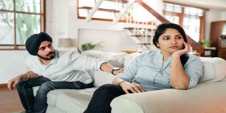 couple sitting on a sofa and ignoring each other, while one person reaches out to the other