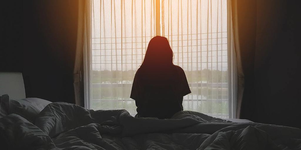 girl sitting on bed looking out the window
