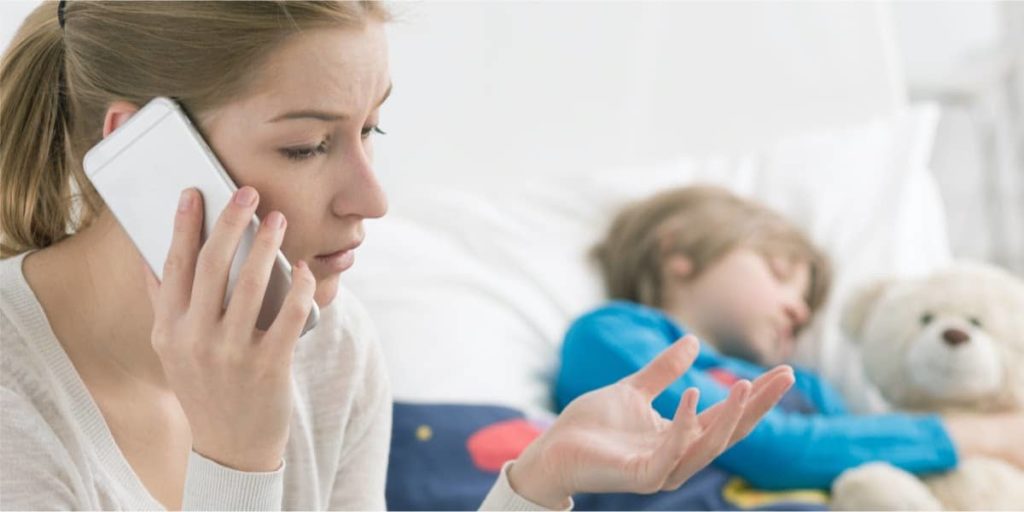 woman talking on phone while her little boy is asleep on the sofa beside her