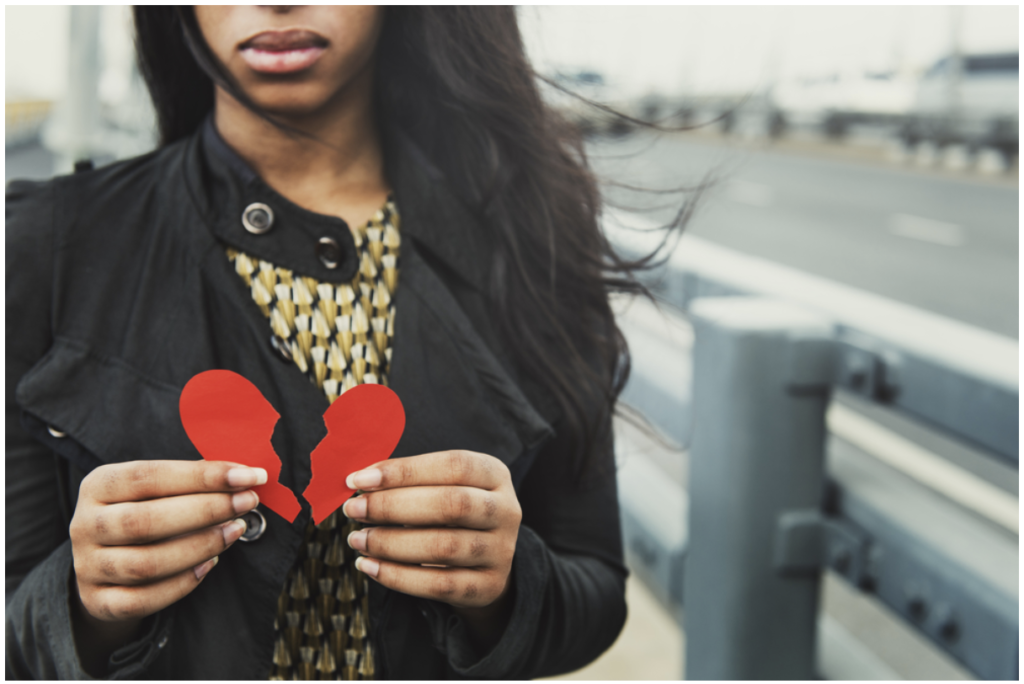 a woman holding a broken heart made of paper